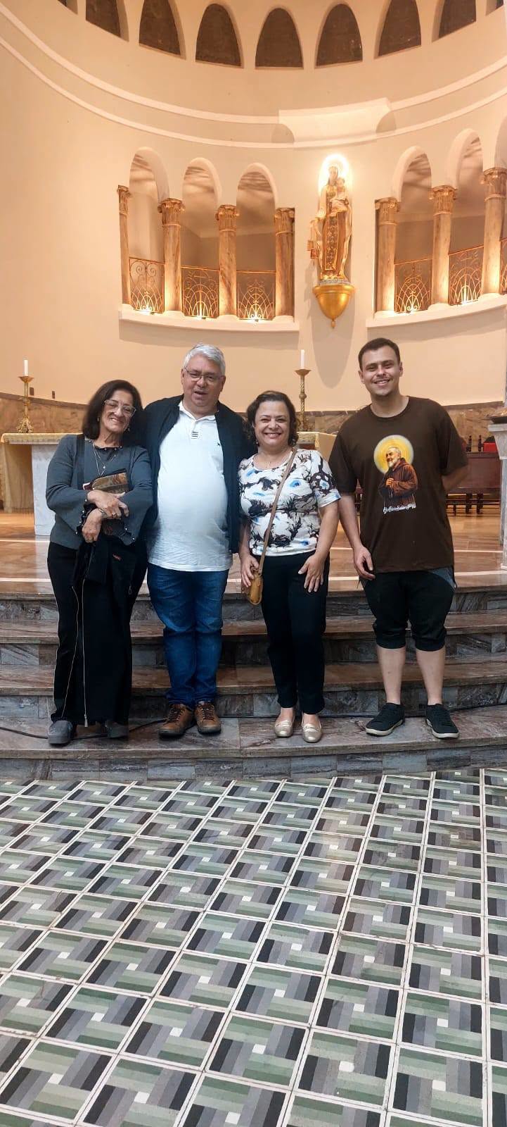 Quatro participantes posando diante do presbitério da igreja
